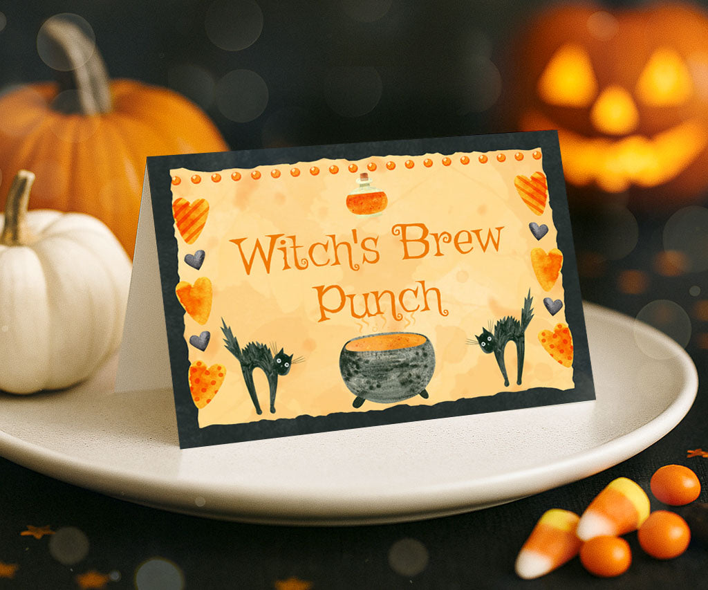 Halloween food tent card with black cats and a witch's cauldron.