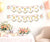 Decorative banner with 'Baby in Bloom' text in a room with flowers and balloons.