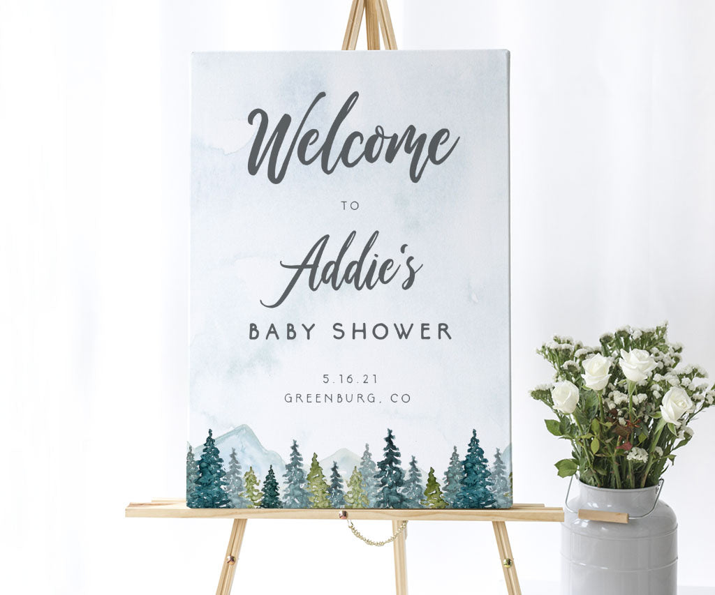 Forest and mountains adventure baby shower welcome sign on an easel.