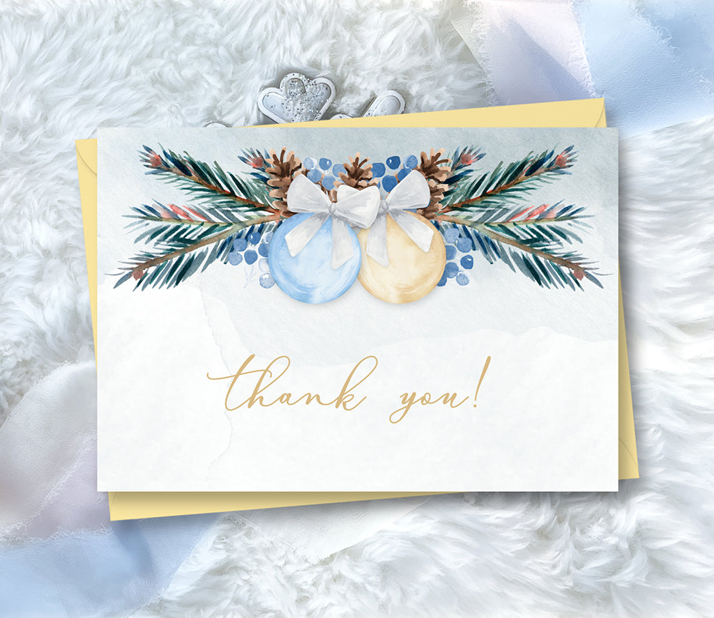 Winter baby shower thank you card with blue and gold ornaments and pine greenery.