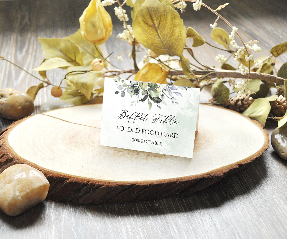 Greenery baby shower folded buffet food card shown sitting on slice of wood